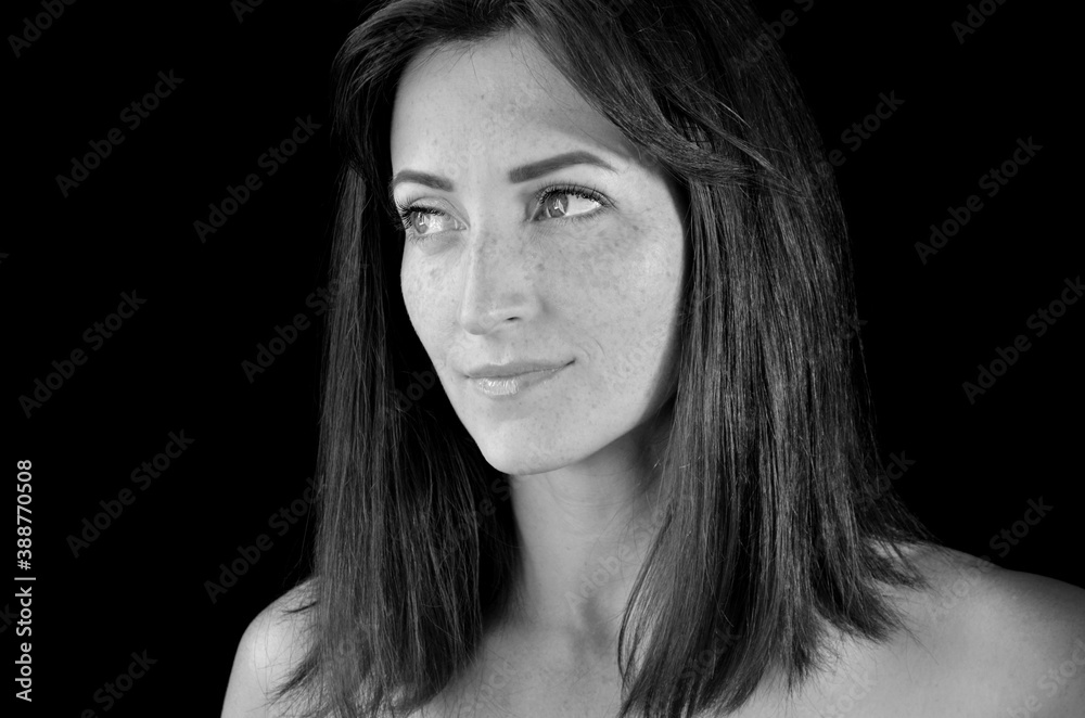 White woman with long hair with eyelash extensions on dark background looking right on black and white