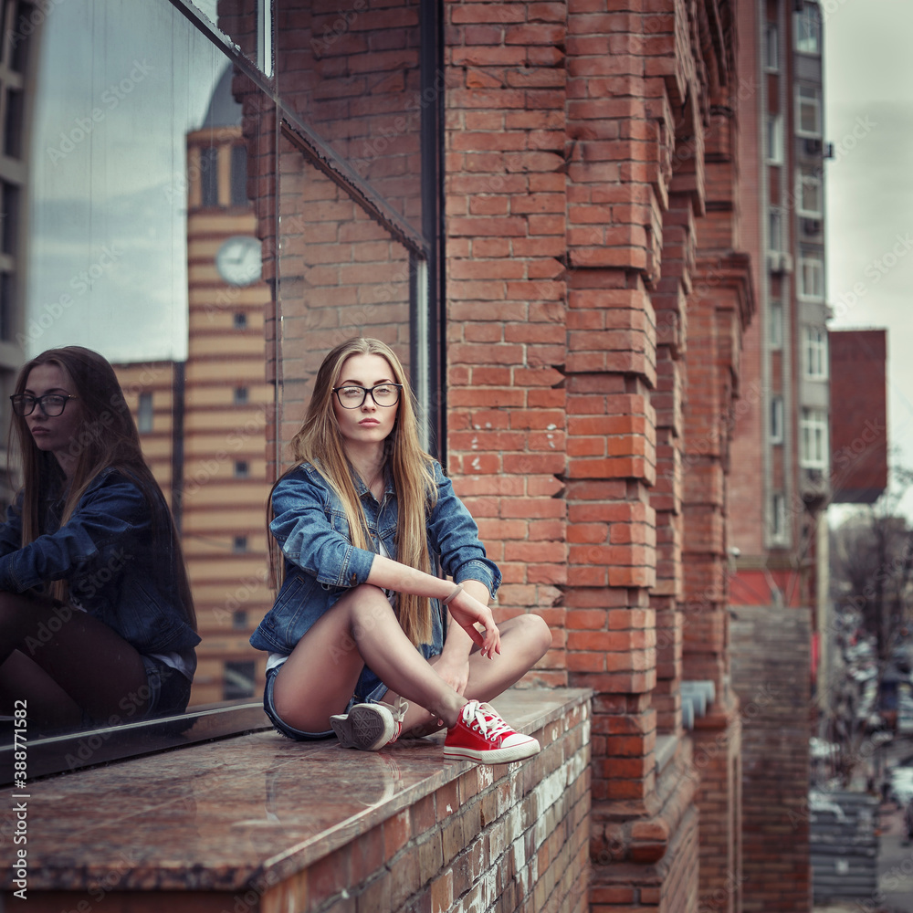 Outdoor lifestyle portrait of pretty young sitting girl, wearing in hipster swag grunge style urban background. Retro vintage toned image, film simulation.