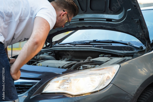 A man looks under the hood of a car for troubleshooting.