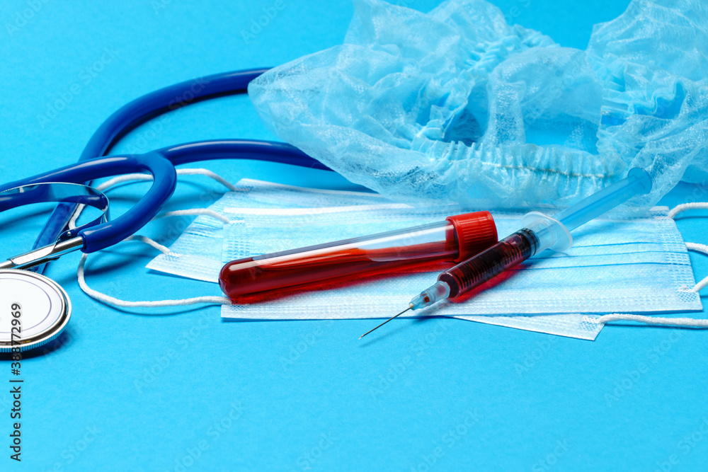 Medical lab concept - Covid-19 blood sample in test tube and syringe on blue background Medical lab concept - Covid-19 blood sample in test tube and syringe on blue background