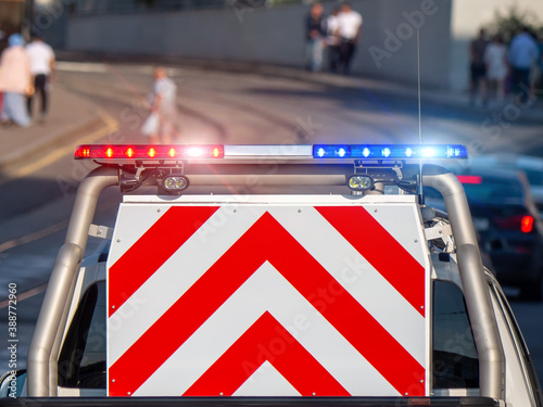 A police patrol pickup truck with a flasher and a striped warning sign in the back on a city street