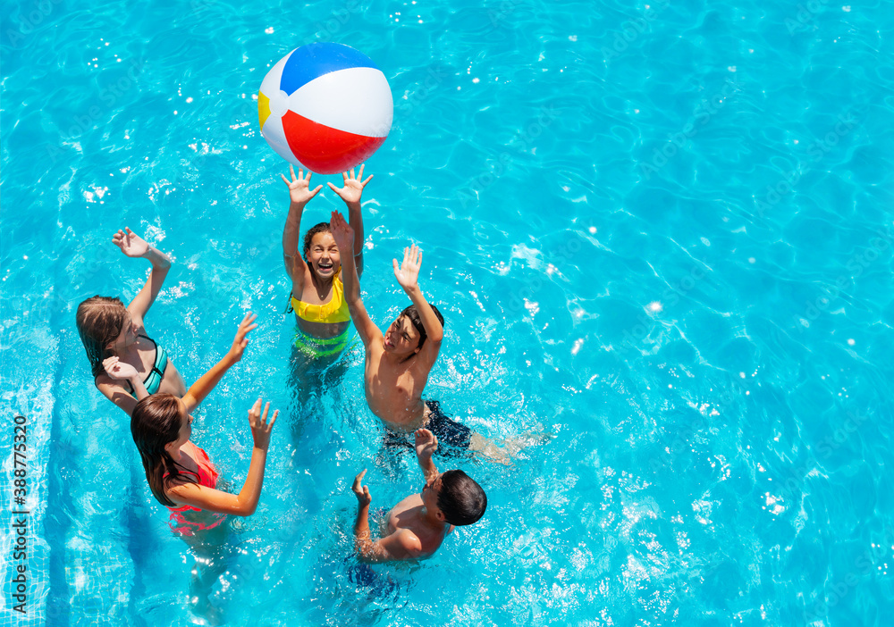Group of kids in swimming pool play with inflatable ball view from above reaching hands up - obrazy, fototapety, plakaty 