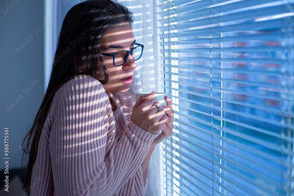 Young woman with the coronavirus in the quarantine looking through the hospital window Young woman with the coronavirus in the quarantine looking through the hospital window