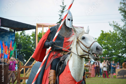A rider in armor with a spear on a horse. The action takes place at a medieval festival.