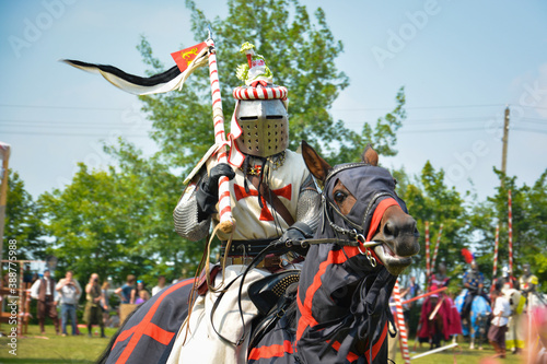 A rider in armor with a spear on a horse. The action takes place at a medieval festival.