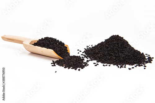 Black cumin seeds in a wooden spoon. Stack of  black cumin seedson a white background.