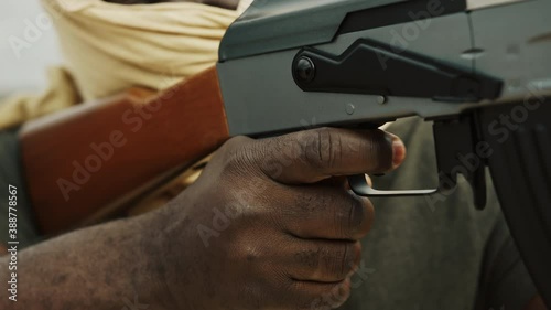 Close up, unrecognizable black man with head covering pulling triger of  machine gun. Concept of terrorism photo