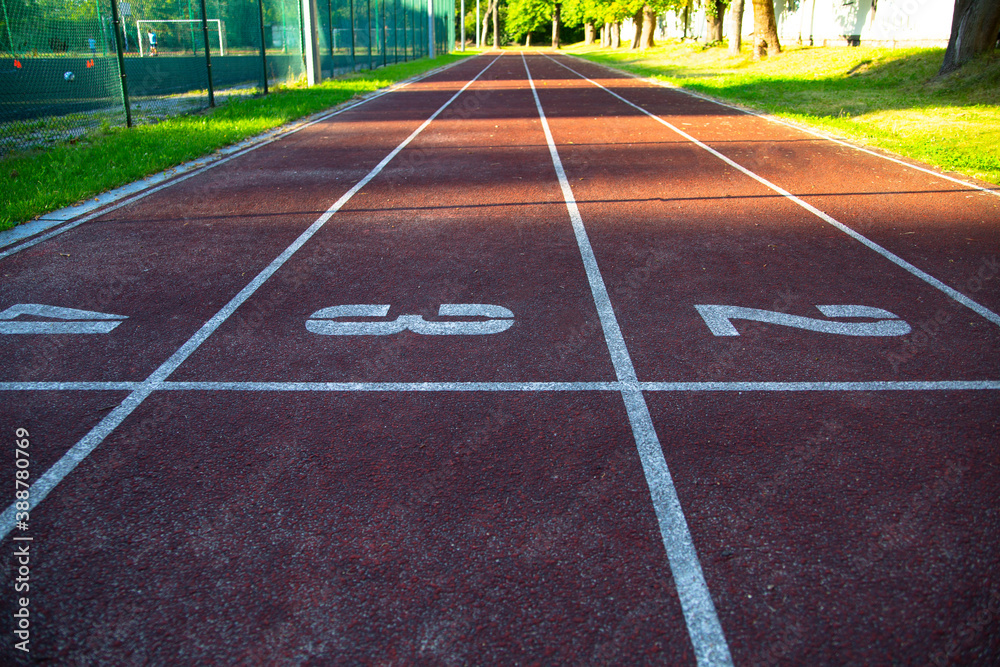 Horizontal view of an athletic running track with visible starting, finish line, outdoor on a sunny day.