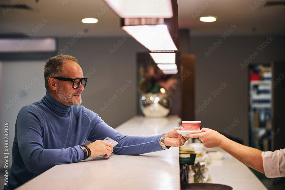 Pleased customer looking at his drink served by a barista