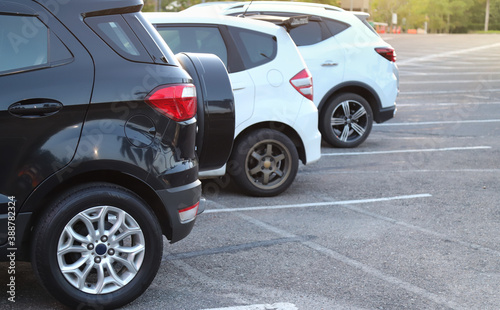 Closeup of rear or back side of black car and other cars parking in parking lot in twilight evening.  © Amphon