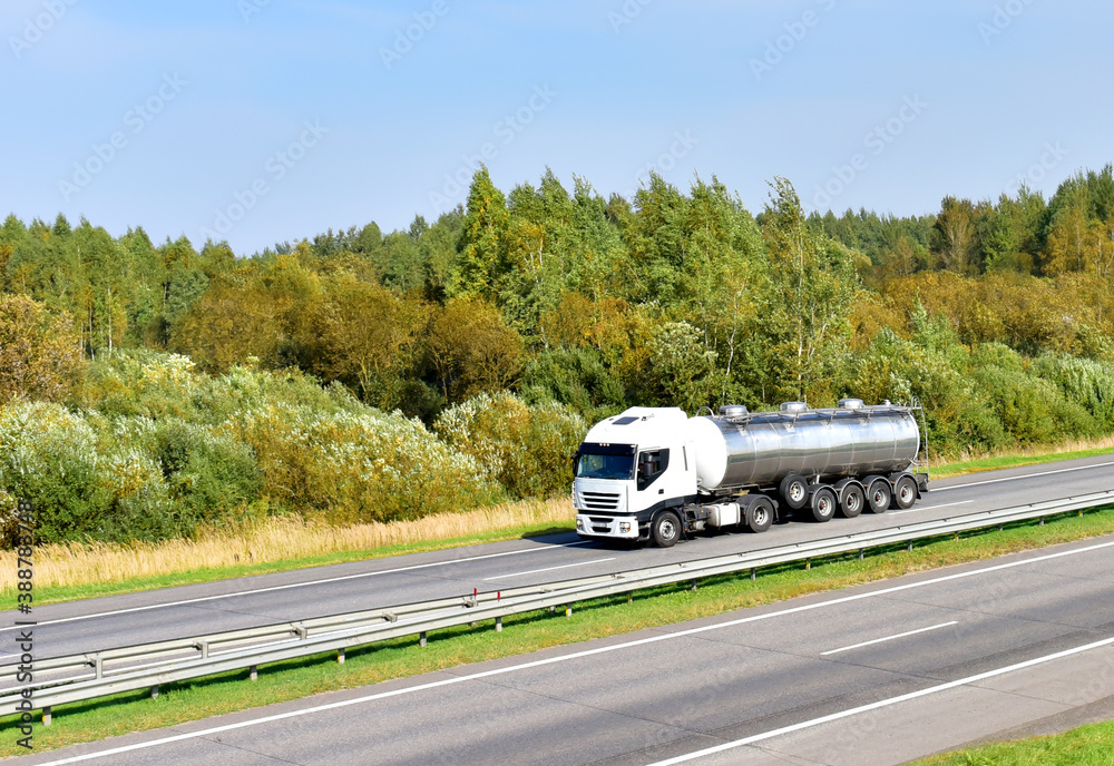 Isothermal Tank truck driving on highway. Oil and Gas Transportation and Logistics. Metal chrome cistern tanker with petrochemicals products. Liquid Chemical Freight. Soft focus possible granularity Isothermal Tank truck driving on highway. Oil and Gas Transportation and Logistics. Metal chrome cistern tanker with petrochemicals products. Liquid Chemical Freight. Soft focus possible granularity