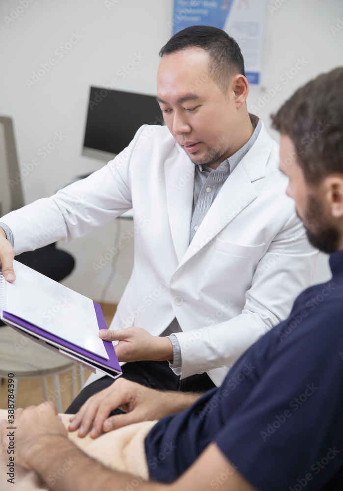 Obraz premium Young handsome man in beauty salon consults with beautician on anti-aging treatments. Doctor writing notes on clipboard and explain procedures to the patient