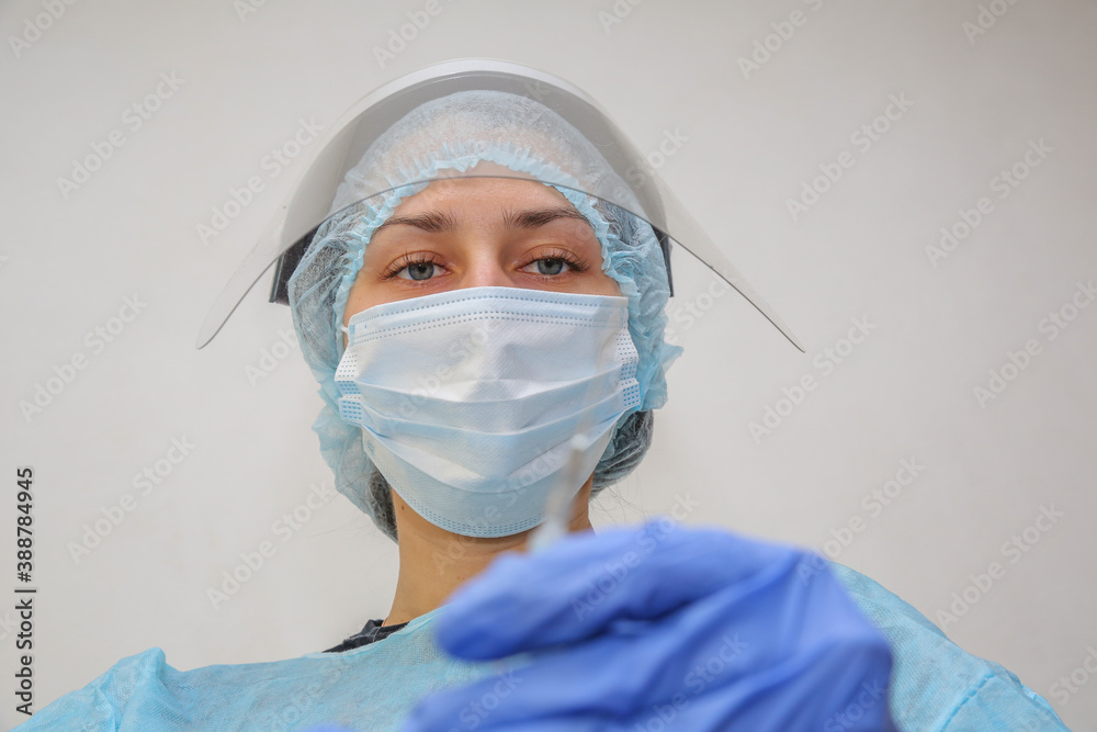 young woman doctor nurse in a protective mask with a syringe in her hand