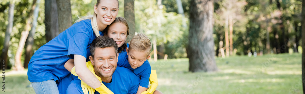 family of volunteers embracing and looking at camera in forest, ecology concept, banner family of volunteers embracing and looking at camera in forest, ecology concept, banner
