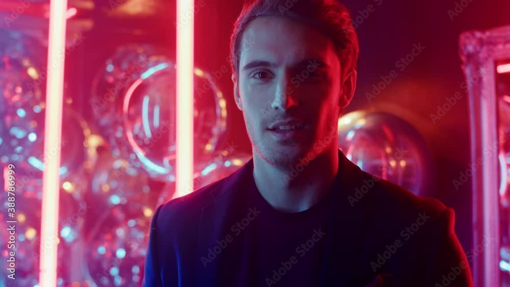 Shy guy looking at camera in nightclub. Male person posing on neon background Shy guy looking at camera in nightclub. Male person posing on neon background