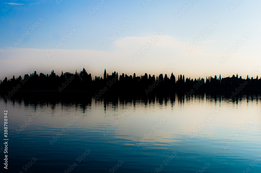 I cipressi dell'isola monastero di San Francesco del Deserto, nella laguna di Venezia, si riflettono nell'acqua immobile