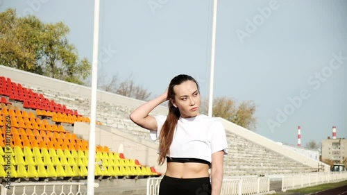 slim young fitness runner with ponytail in sportswear walking on running track. fit sportive asian female in activewear walks along statium tribune. sports, healthy lifestyle. sportswoman portrait photo