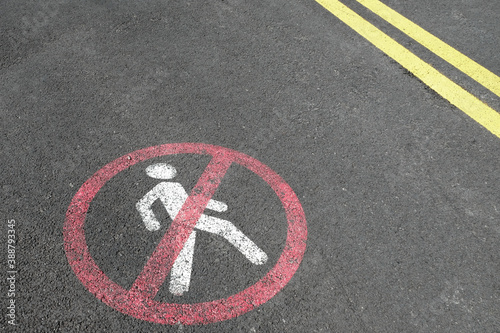 White road markup signal and yellow lines on concrete asphalt. Transportation restrictions on the way. No pedestrians allowed, no walking, driving and riding bicycles only. Red painted crossed sign. © Juliet Dreamhunter