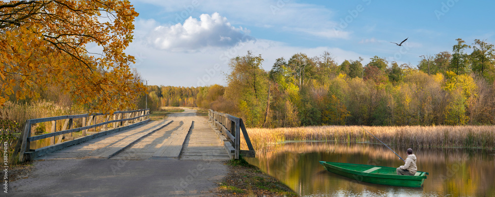 The photo shows a bridge, a river with a boat and a fisherman, a bird against a blue sky The photo shows a bridge, a river with a boat and a fisherman, a bird against a blue sky