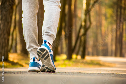 Legs close up on forest background. Walking girl. A sportive girl walks through the forest. Bottom view. Sport