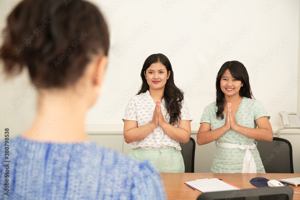Two asian women showing namaste greeting gesture to a customer to avoid personal contact due to epidemic covid coronavirus. Healthcare and medicine Two asian women showing namaste greeting gesture to a customer to avoid personal contact due to epidemic covid coronavirus. Healthcare and medicine