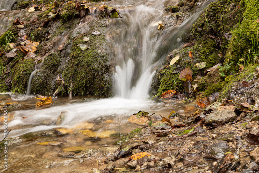 Waterfall in autumn with falling leaves, lots of water