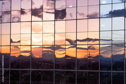 sunset reflection in windows of modern building with windows and orange and pink colored windows texture background