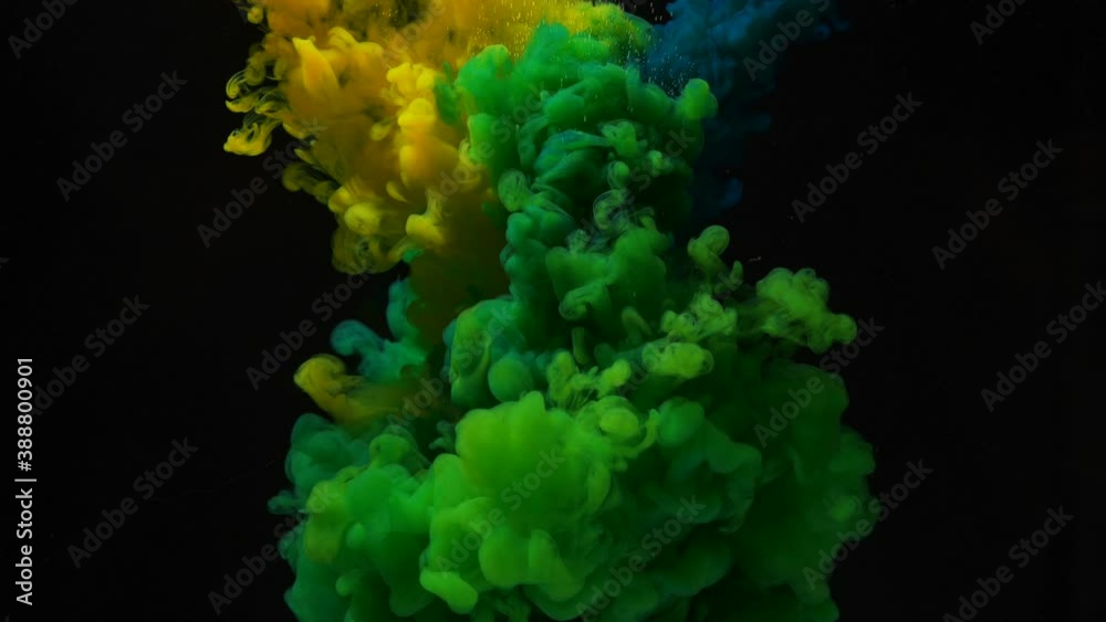 Mixing bright yellow and blue paints to have juicy green color under clear water on black background extreme close view