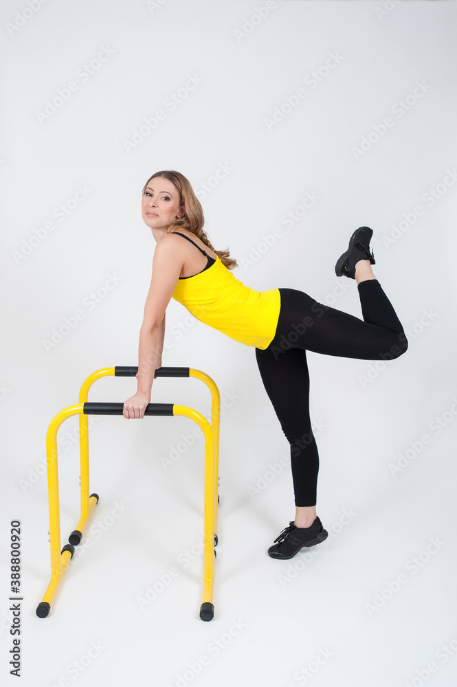 Obraz premium Woman doing exercises with high yellow floor bars on a white background