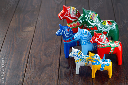 Swedish traditional souvenir wooden dala horses, hand craft made and painted, different colors and sizes, on wooden background,  horizontal, copy space photo