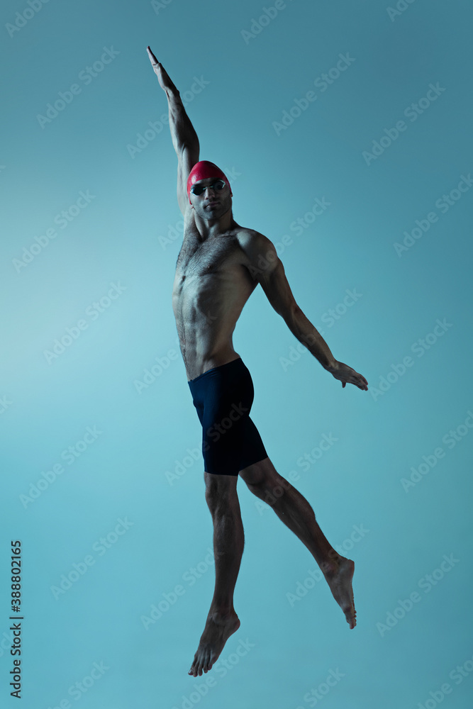 Professional caucasian male swimmer with hat and goggles practicing and