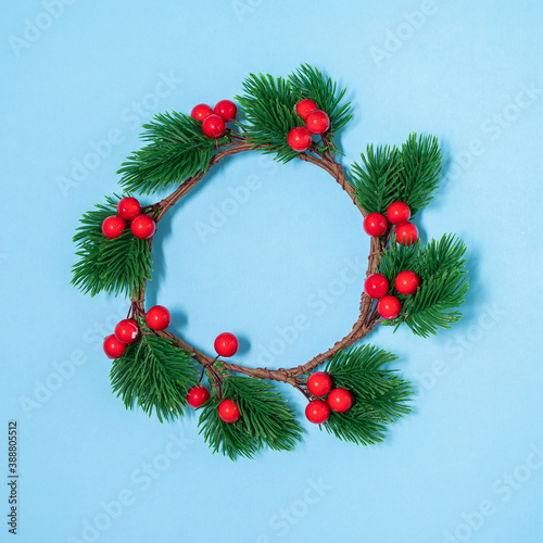Christmas flat lay circle frame from xmas berries and fir-tree branches decorations and pine cones on the blue