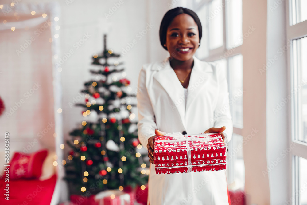 Beautiful girl in a decorated room. Woman near Christmas tree. Black ladyin a white suit Beautiful girl in a decorated room. Woman near Christmas tree. Black ladyin a white suit