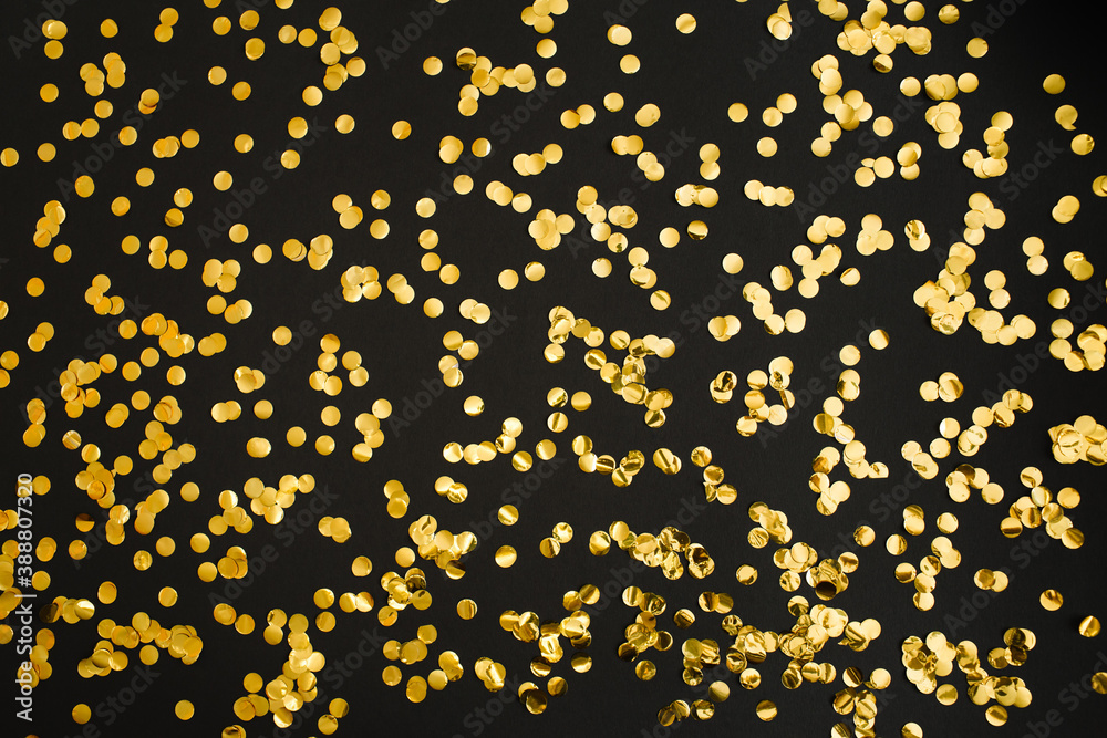 Golden confetti on black background. Festive holiday backdrop. Birthday congratulations Christmas New Year. Flat lay, top view, copy space. Golden confetti on black background. Festive holiday backdrop. Birthday congratulations Christmas New Year. Flat lay, top view, copy space.