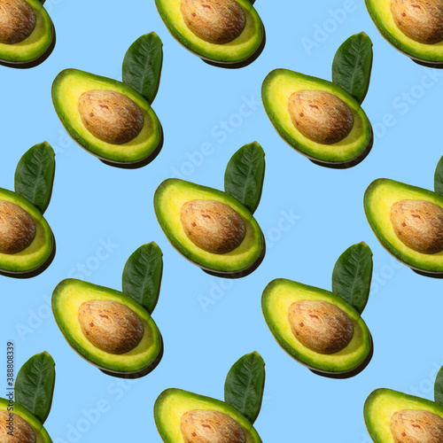 Seamless pattern of half avocado with stone and leaf  shadow  blue background. Healthy vegetarian food  background for design.