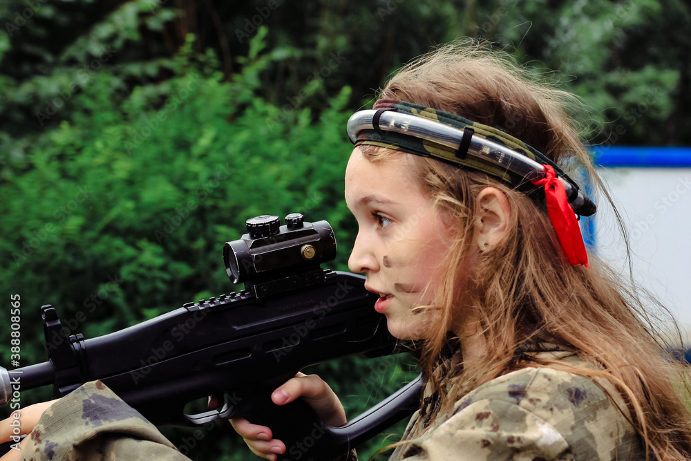 Teenage girl playing in lasertag shooting game in open air. Weapon in the hands of people. War simulation.
