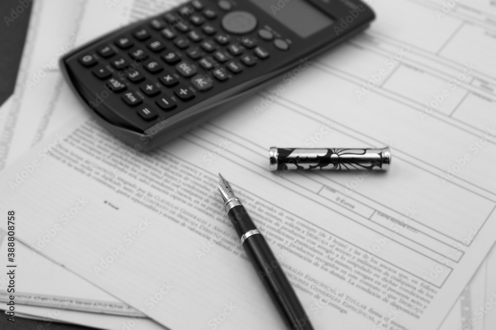 A fountain pen and a calculator on documents ready to be signed A fountain pen and a calculator on documents ready to be signed