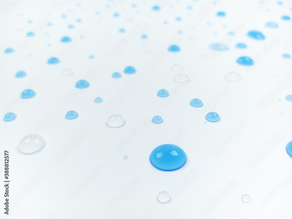 Selective focus of blue and clear water drops on white background with blurred effect.