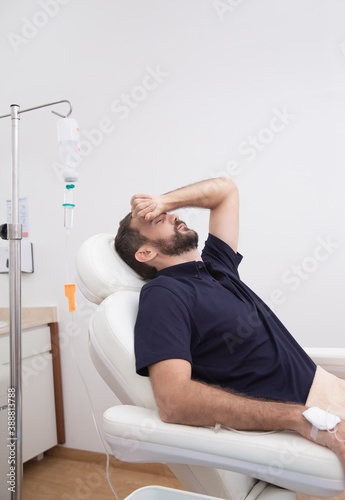 Fotografija Sick, dehydrated or hangover patient man receiving vitamin IV infusion drip in hospital or beauty salon
