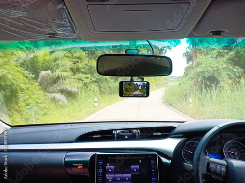 Chiang rai, Thailand, October 26, 2020: Car camera, rearview mirror, digital touchscreen display, and steering wheel inside the car with nature and road view.