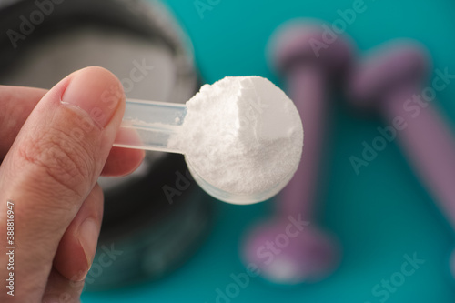 L-Glutamine supplement. Man holding a scoop of  L-Glutamine powder in his hand. Close up. photo