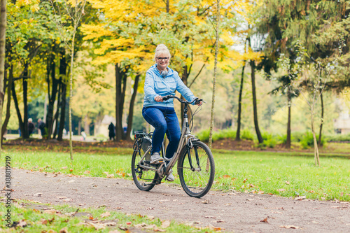 senior woman walking in the park with a bicycle, sunny day © Liubomir