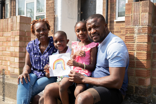 Portrait happy family with rainbow drawing on sunny front stoop photo