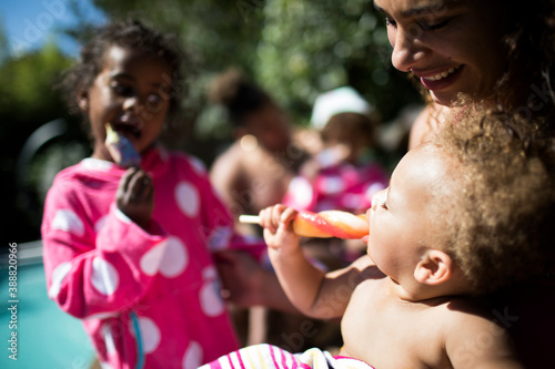 Happy family enjoying popsicles at sunny summer poolside photo