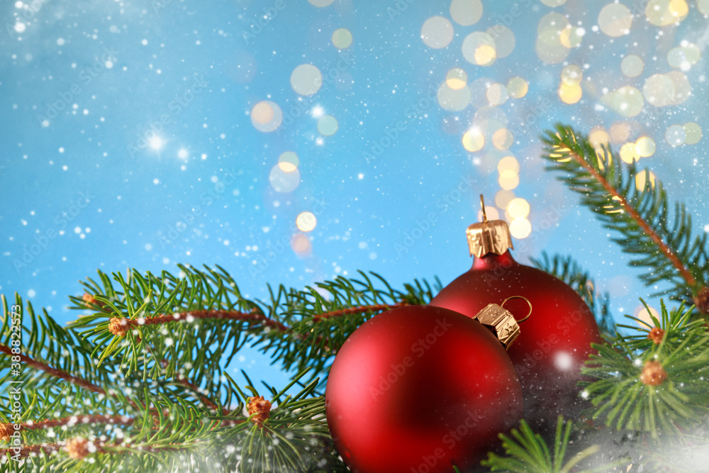 Obraz premium Christmas greeting card with red balls and fir branch on blue bokeh background