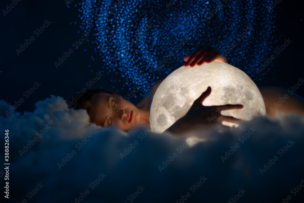 Tender young naked woman sleeps and hugs the moon on amazing starry sky with and soft clouds background. Fairy tale. Artistic photography. - obrazy, fototapety, plakaty 