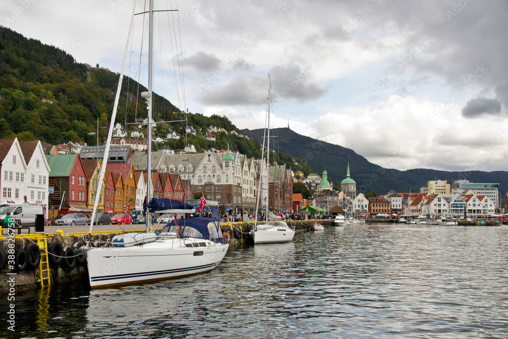 Boats and historic buildings along the Bryggen (wharf)  in  Bergen, Norway under cloudy sky