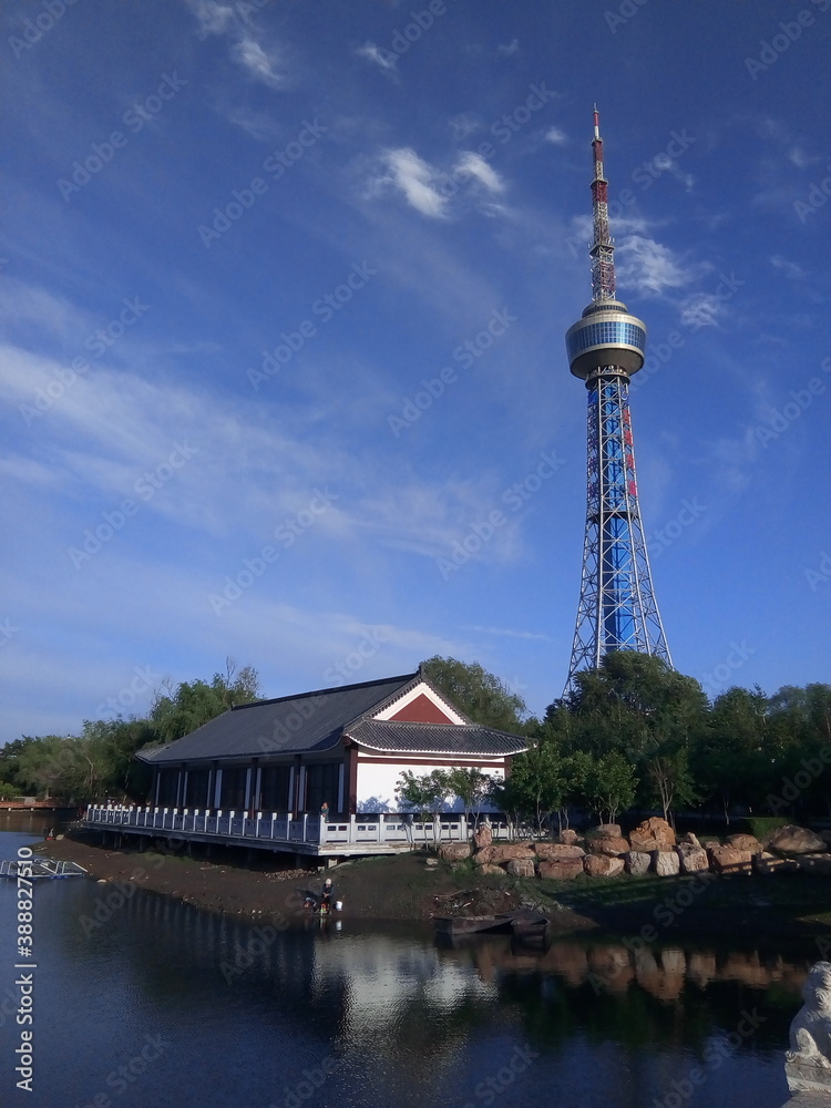 Changchun, Jilin/China - June 16 2019: A TV tower and Chinese traditional building by a lake in city