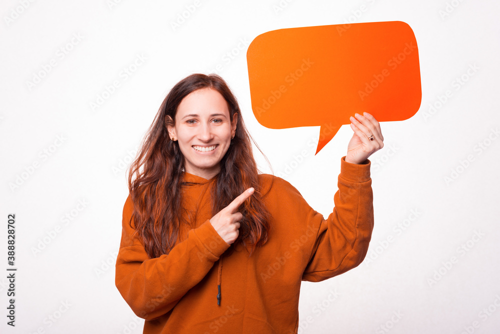A picture of a cheerful young woman holding a speech bubble and is pointing at it . A picture of a cheerful young woman holding a speech bubble and is pointing at it .