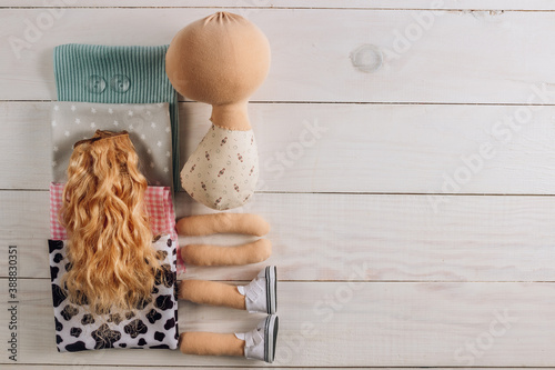 Textile doll in the sewing process with accessories and materials: fabric, thread, needle on white wooden background photo